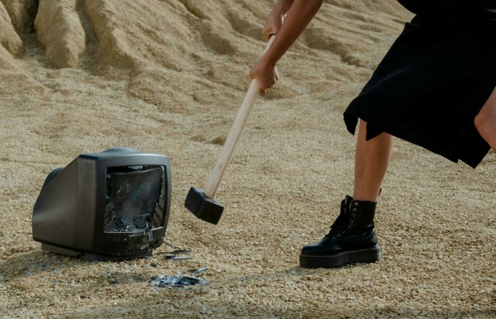 Person swinging a bat at a glass bottle in a smash room